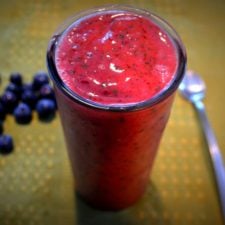 berry and green smoothie with a green background