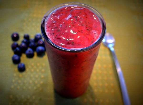 berry and green smoothie with a green background