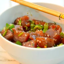 ahi tuna poke in white bowl with chopsticks on side