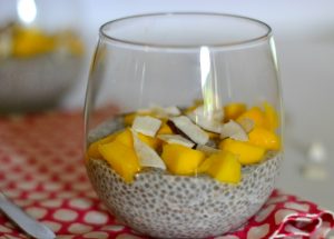 glass full of chia pudding topped with mango and dried coconut