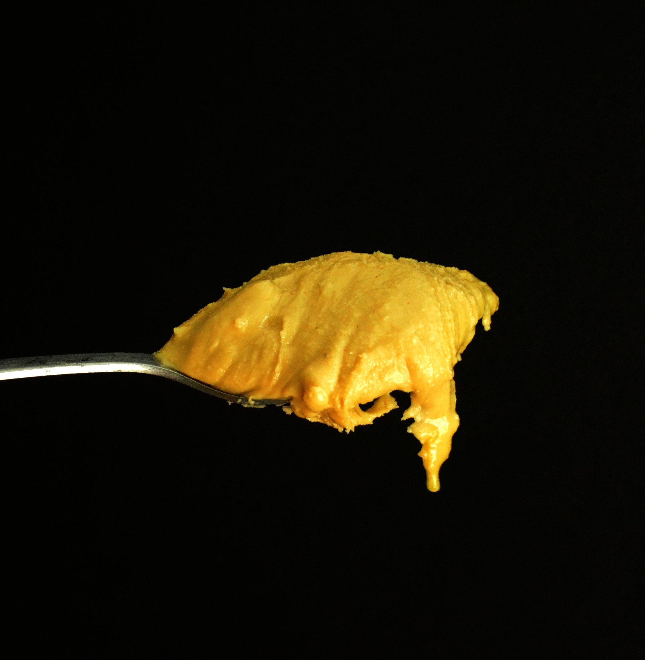 black background with cashew butter covered spoon in the foreground