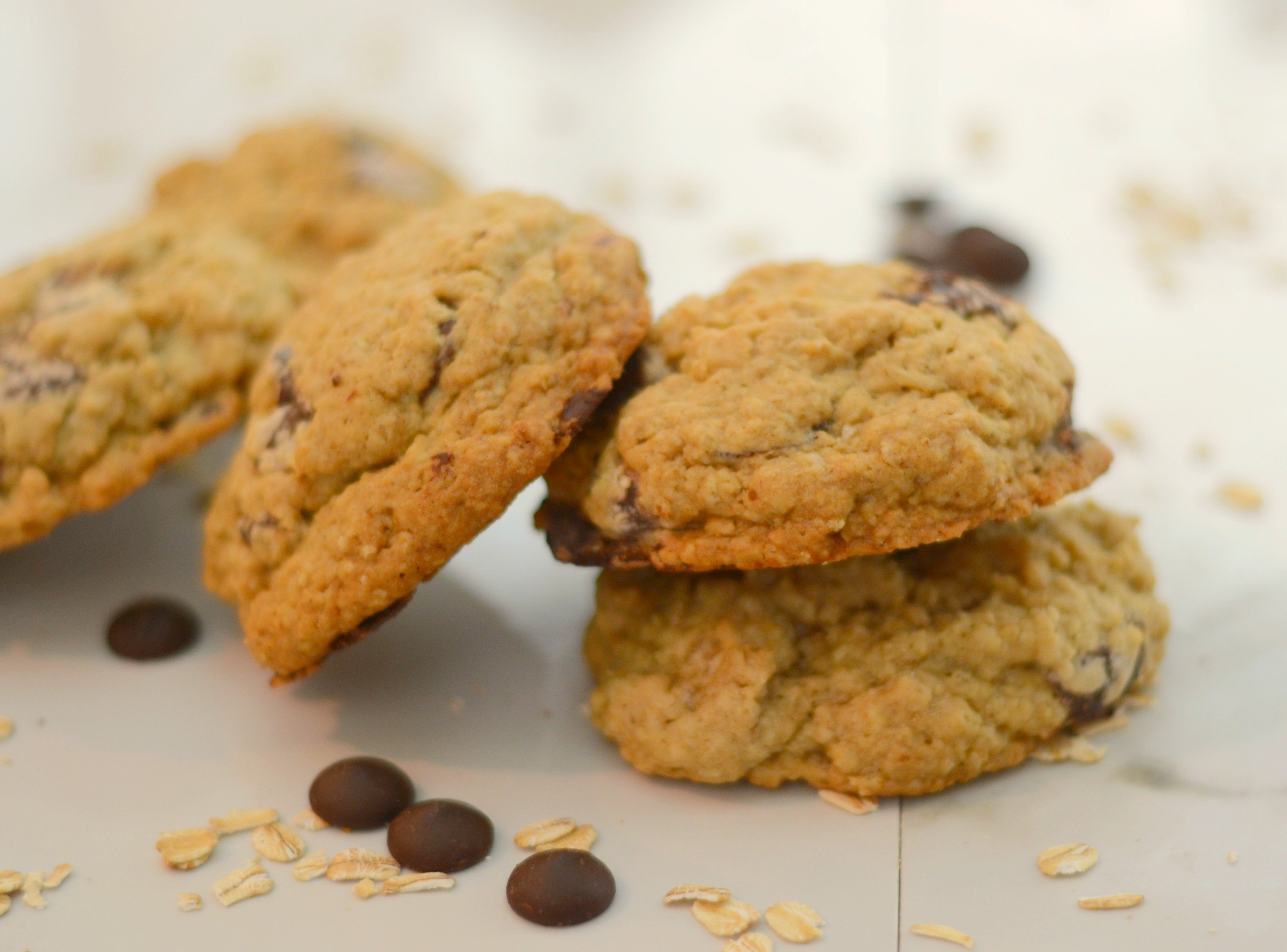 a toppled stack of oatmeal chocolate chip cookies on a white background