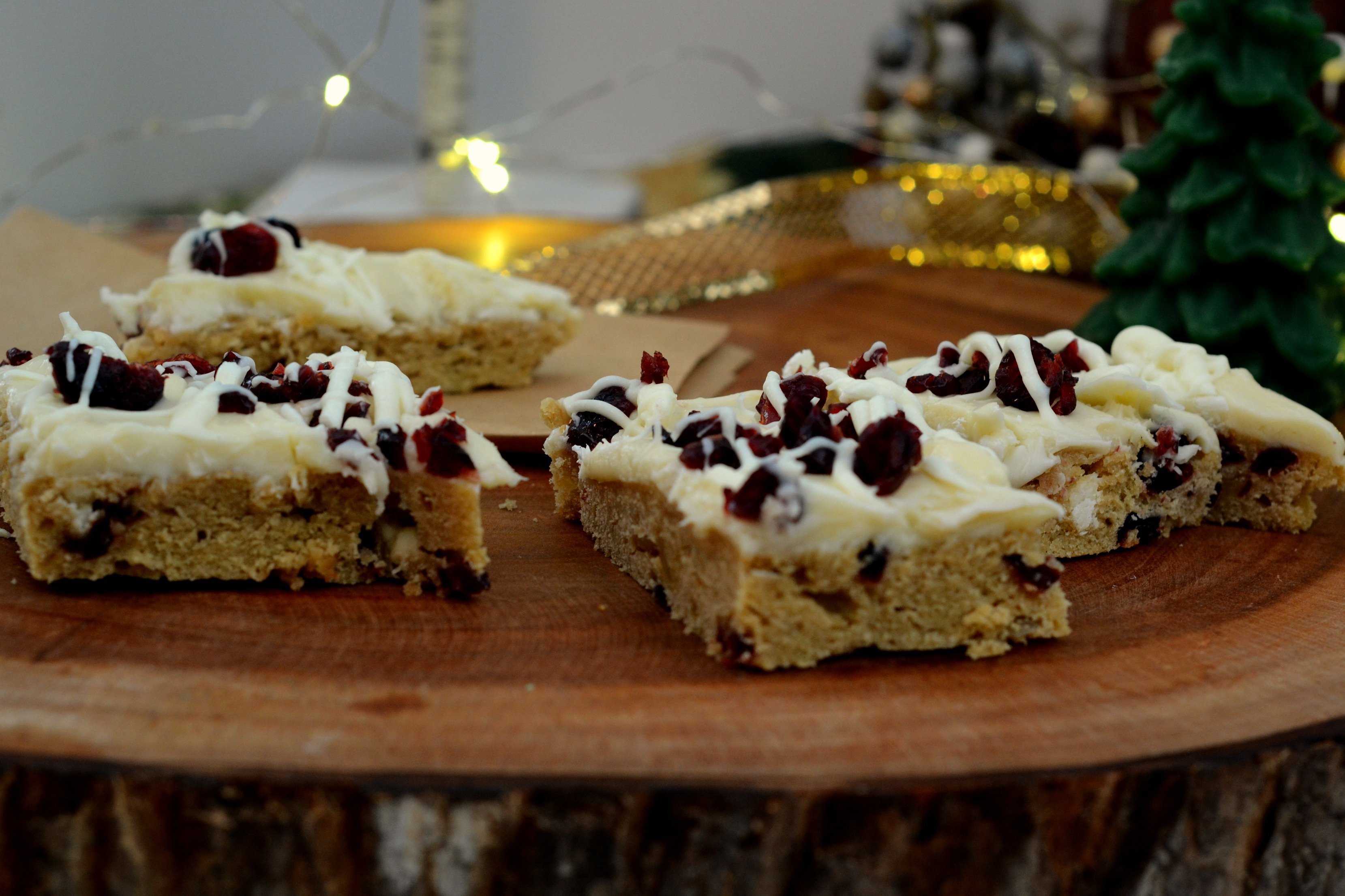 White Brownies with Frosting with Cranberries and a drizzle of white chocolate, holiday decorations in the background