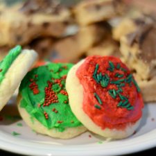 A plate of festive holiday cookies, featuring red and green soft sugar cookies with Christmas sprinkles.