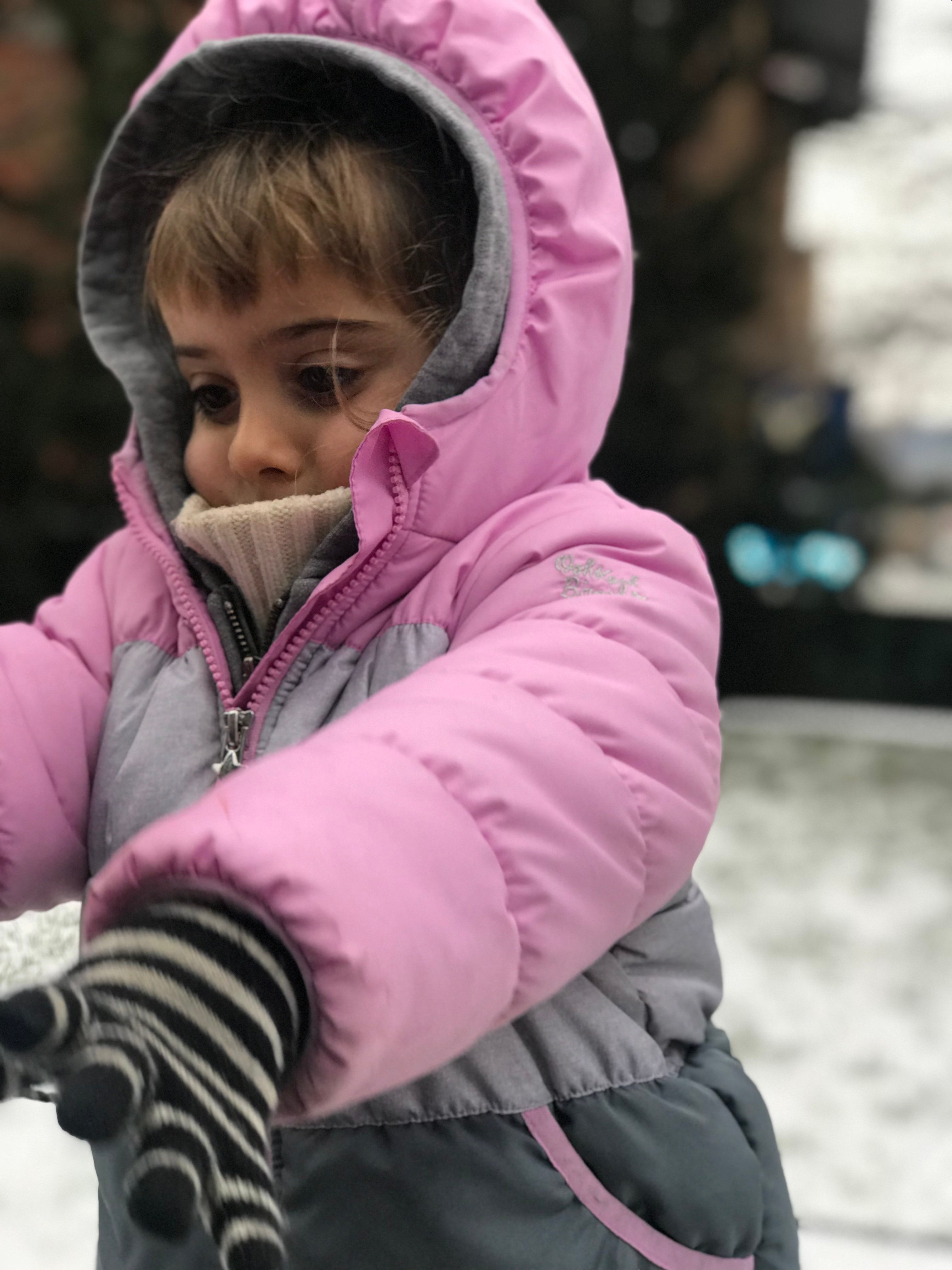 toddler bundled up in pink coat with snow in background, new york city highline park