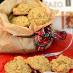 brown paper bag with mini oatmeal cookies pouring out of it surrounded by Christmas decorations