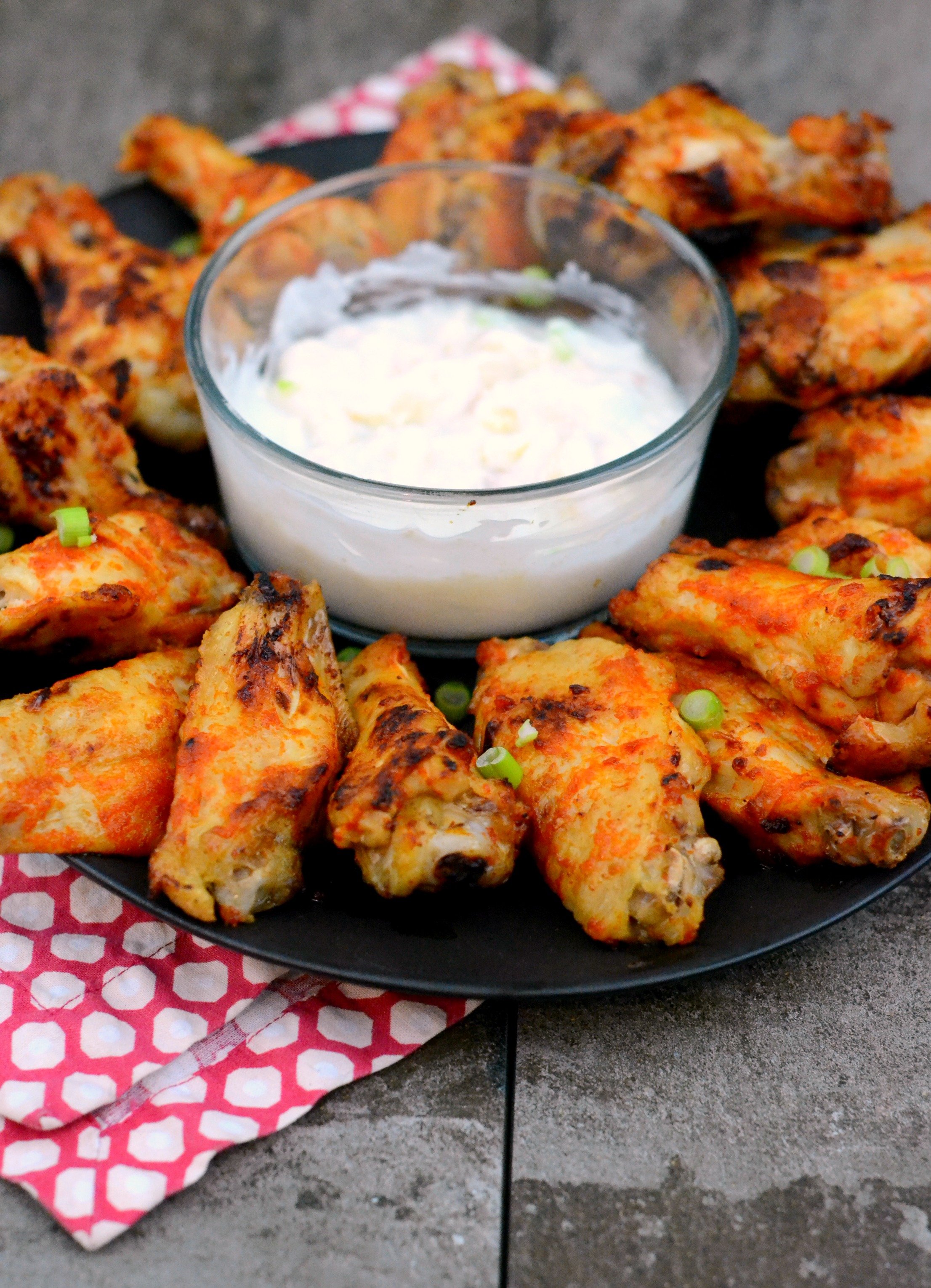 Spicy baked paleo wings arranged in a circle with a dipping sauce in the middle. 