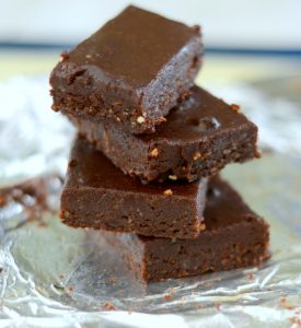 Stack of four raw, vegan brownies with a tinfoil background