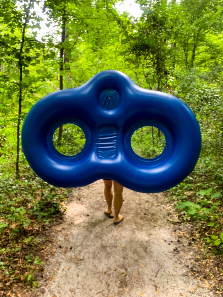 Woman walking down trail holding intertube
