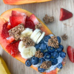half of papaya filed with berries and bananas toped with granola
