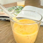 Mango Peach Smoothie in the foreground with a cookbook in the background.
