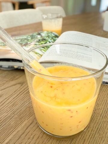 Mango Peach Smoothie in the foreground with a cookbook in the background.