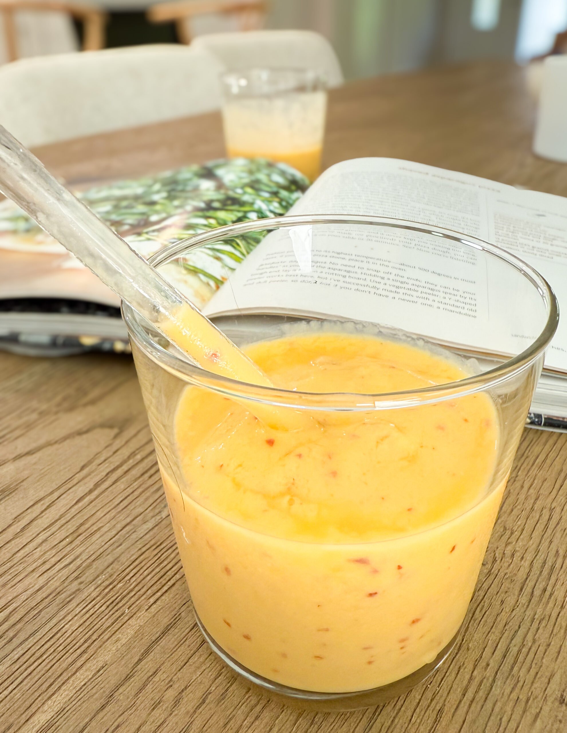 Mango Peach Smoothie in the foreground with a cookbook in the background. 